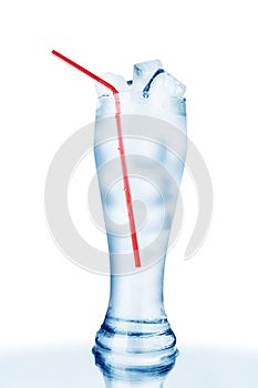 One full transparent glass of cold crystal clear water, red drinking straw, ice cubes on white background isolated close up