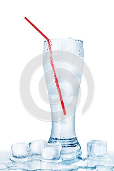 One full transparent glass of cold crystal clear water, red drinking straw, melting ice cubes, white background isolated closeup