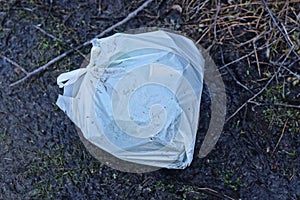 one full white plastic bag lies on the black ground