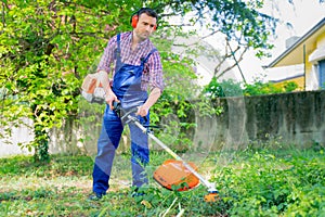 One gardener mowing grass using brushcutter in the garden