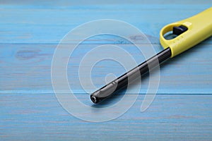 One gas lighter on light blue wooden table, space for text