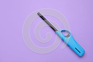 One gas lighter on violet background, top view. Space for text