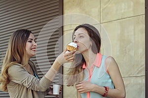 One girl feeds another while they drink coffee