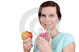 One girl holds apple and vitamins in hand