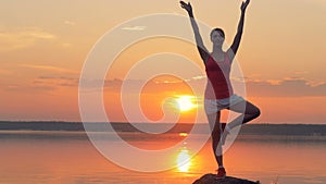 One girl meditates on a sunset background.