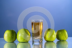 One glass of apple juice with green apples in the beautiful bluebackground. Reflected surface. Summer day. Good mood.