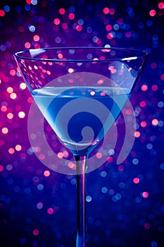 One glass blue cocktail on blue and violet tint light background
