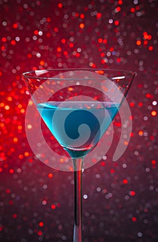 One glass blue cocktail on red tint light background