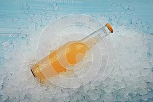 One glass bottle of orange drink on crushed ice