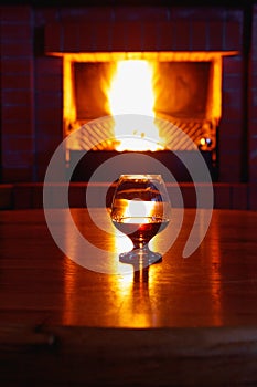 One glass of cognac on background of old brick fireplace