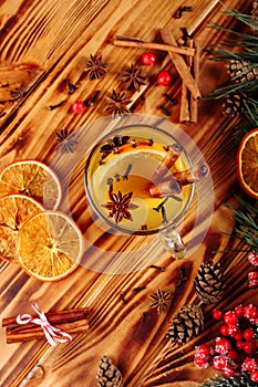 One glass cup of christmas mulled wine or gluhwein with spices and orange slices on rustic wooden table top view