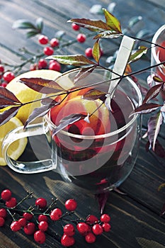 One glass cup of hot berry tea in autumn leaves decoration, winter autumn mood, citrus red tea