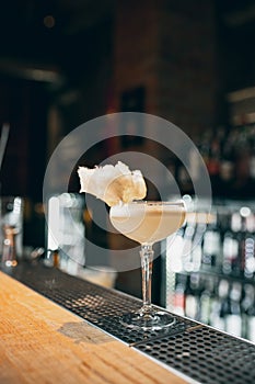 One glass filled with alcohol cocktail or shampagne decorated with cotton candy standing on bar counter