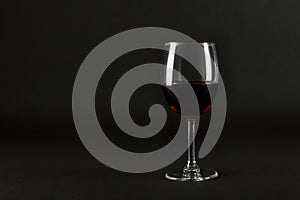 One glass goblet of red wine on black homogeneous background