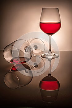 One glass half full the second lies, spilled wine, two red wine glasses on a white background