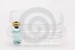 One glass vaccine bottle inside an opened translucent plastic box for ten vaccine bottles