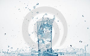 One glass of water with splash from falling ice cube, white background, isolated object