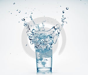 One glass of water with splash from falling ice cube, white background, isolated object