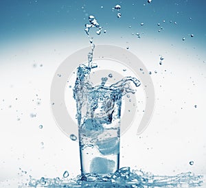 One glass of water with splash from falling ice cube, white background, isolated object