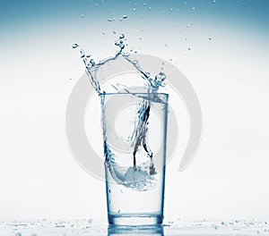 One glass of water with splash from falling ice cube, white background, isolated object