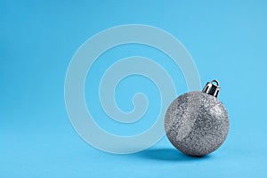 One glitter Christmas ball on light blue background. Space for text