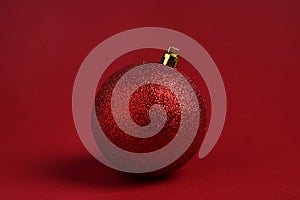 One glitter Christmas ball on red background