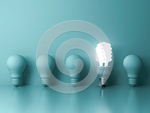 One glowing compact fluorescent lightbulb standing out from unlit incandescent bulbs reflection on green background