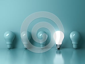 One glowing light bulb standing out from the unlit incandescent bulbs on green background with reflection
