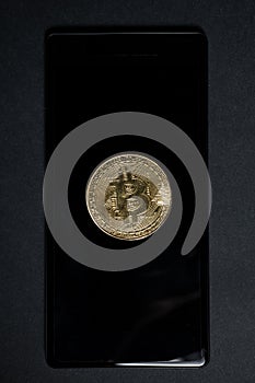 One golden bitcoin on celphone or smartphone screen