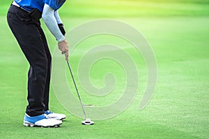 One golf player is putting a putter to the ball to hit the hole