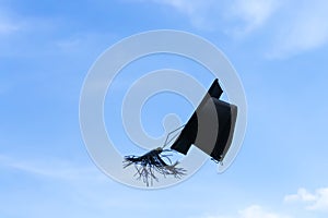 One graduation cap or mortar board thrown up to the air, sky background photo