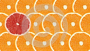 One grapefruit slice stand out of orange fruits