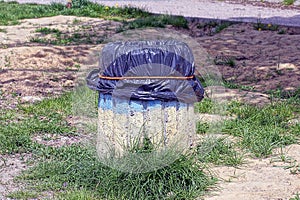 One gray concrete bin with a black plastic bag stands on the ground