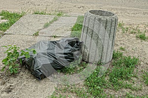 One gray concrete urn and a black plastic bag with garbage