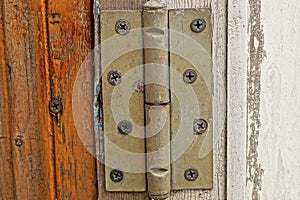 One gray iron door hinge on a brown white plank