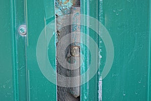 One gray iron door hinge on a green metal door