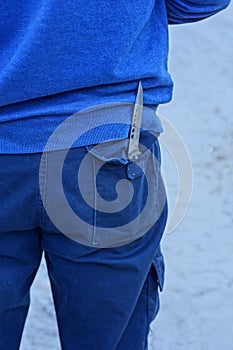 one gray sharp iron knife in a mans blue pants pocket