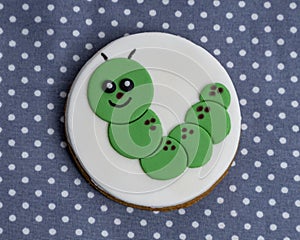 One green caterpillar iced cookie placed on a polka dot table cloth