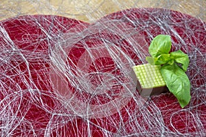 One green mint candy with basil on the heart shape