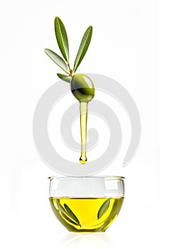 One green olive with leaves dripping olive oil into a transparent glass isolated on a white background photo