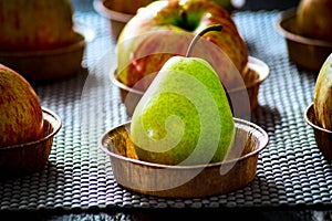 One greenish pear of small size on the background of apples