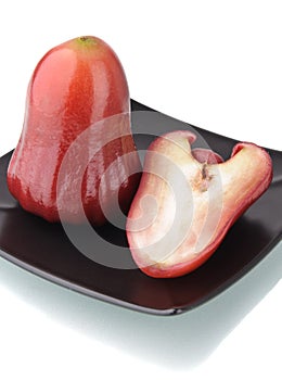 One and a half of red rose apple on black plate