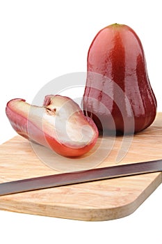 One and a half of red rose apple on chopping board