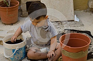 One and a half year old baby boy playing with dirt
