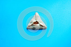 One Hamantashen cookie on a blue background. Festive baking for Purim, Jewish holiday