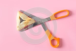 One Hamentashen, Ozen Haman, Purim cookie on pink background for Jewish holiday Purim.