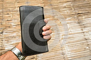 One hand holding a black leather wallet