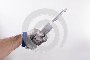 one hand with protective glove, glove of butcher of wire metallic mesh, holding a kitchen knife by the sharp edge, anti cut