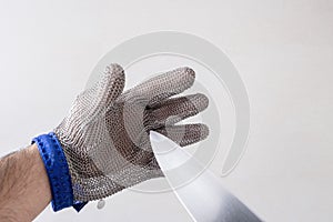 one hand with a steel mesh glove, a sharp stainless steel knife punctures against the glove, protective glove for butchers,