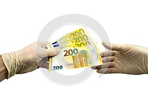 One hand in white protective gloves holds out a bundle of 200 two hundred euro bills to the other hand in a white medical glove.